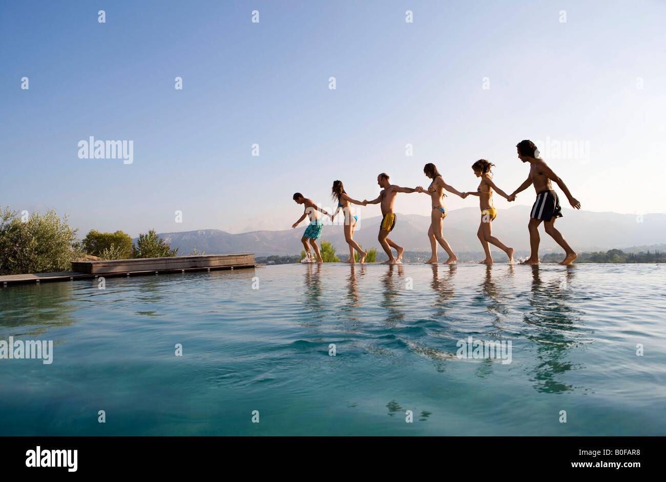 Menschen zu Fuß durch einen Pool, Hand in Hand Stockfoto