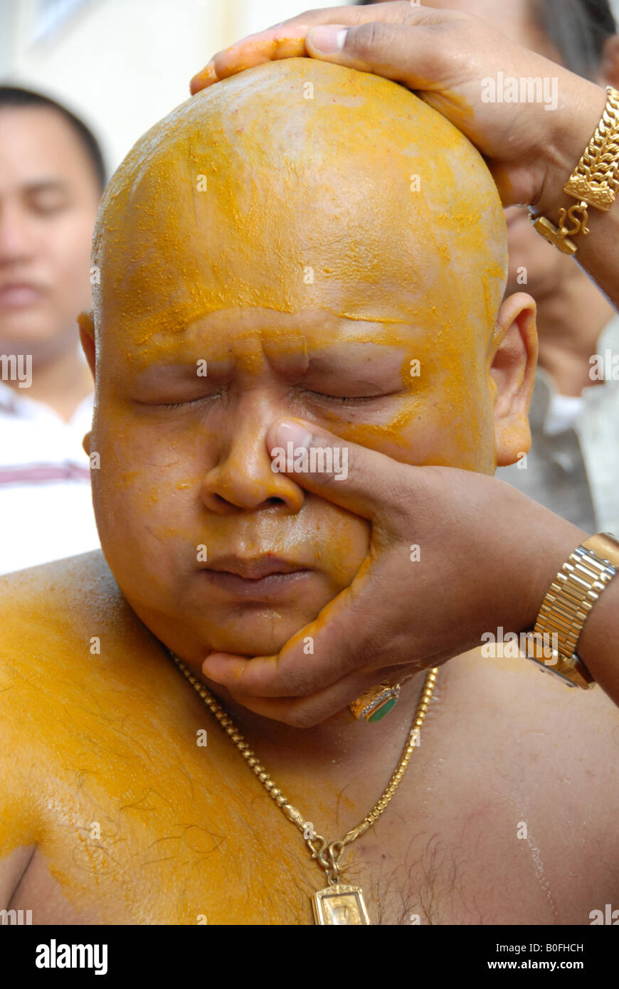 Relative gelten Kurkuma überall auf das Gesicht des Mannes vor buddhistischen Ordination ritual Stockfoto
