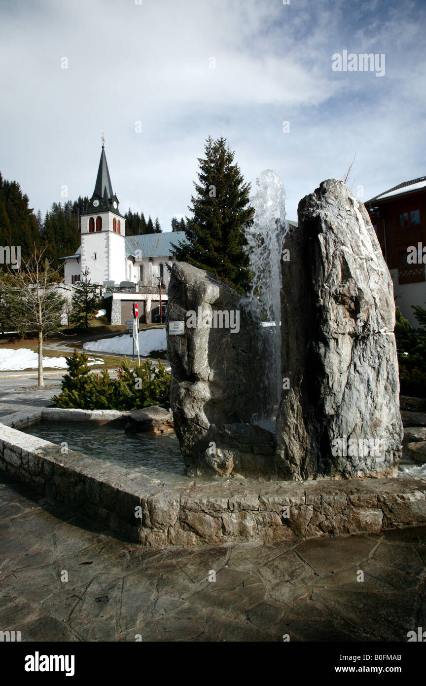 Am frühen Abend s Szene im Dorf von Les Gets, Frankreich. Zeigt einen öffentlichen Brunnen und die Dorfkirche Stockfoto