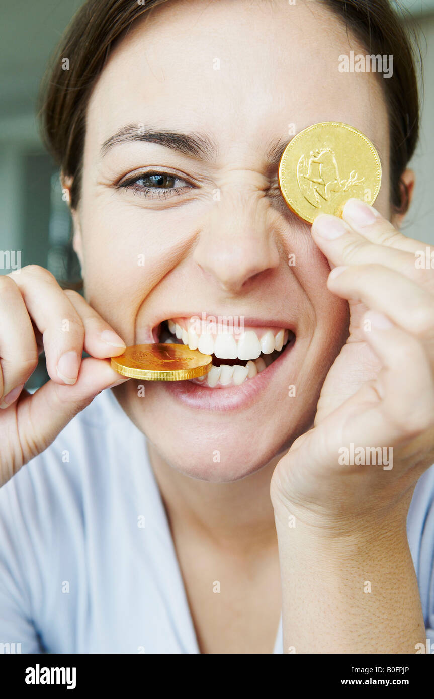 Lustige Frau beißt in Goldmünzen Stockfoto