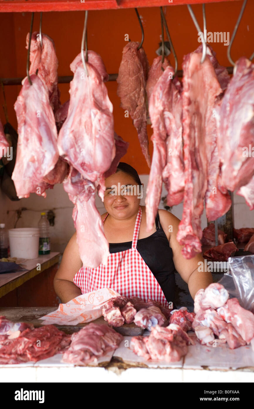 MEXIKANISCHE FRAU WORKING AS METZGER HINTER HÄNGENDES FLEISCH Stockfoto