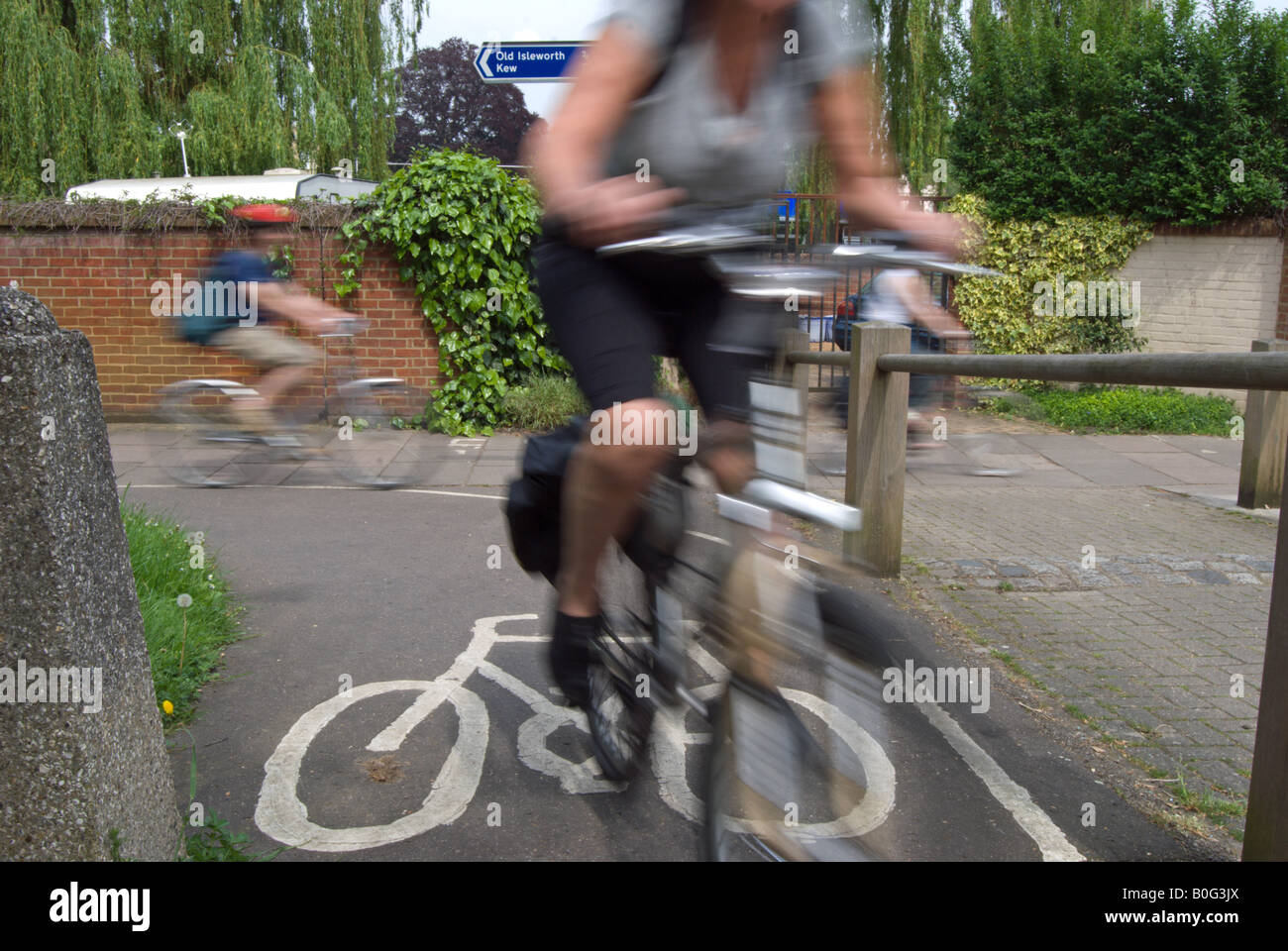 verschwommene weibliche Radsportler, die auf britischen Radweg angegeben mit weißen Fahrrad-Marker, mit zwei anderen Radfahrern im Hintergrund. Stockfoto