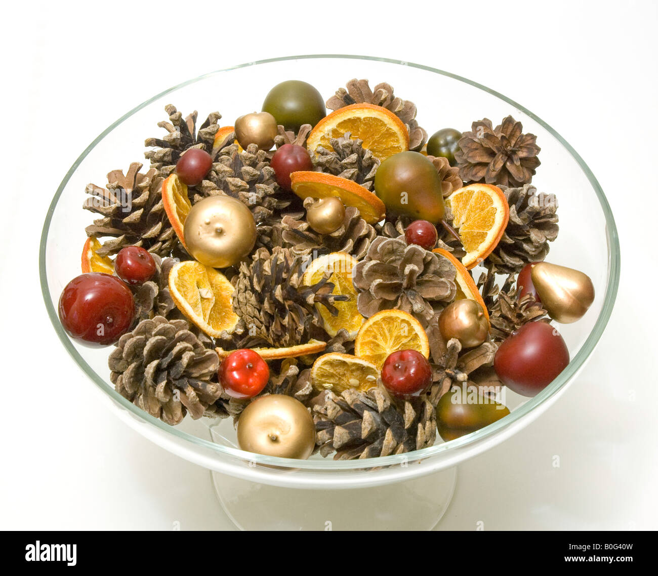 Festliche Mischung aus Tannenzapfen, Orangenscheiben und Kugeln in eine Glasschüssel Stockfoto