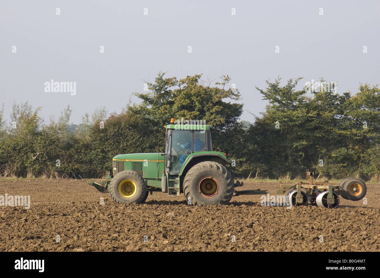 John Deere Traktor rollt ein Acker, Suffolk Stockfoto
