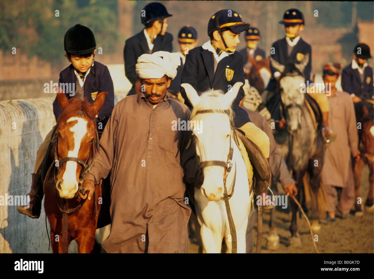 Kinder reiten und Pferde mit einem Lehrer an einer Privatschule, Pakistan. Stockfoto