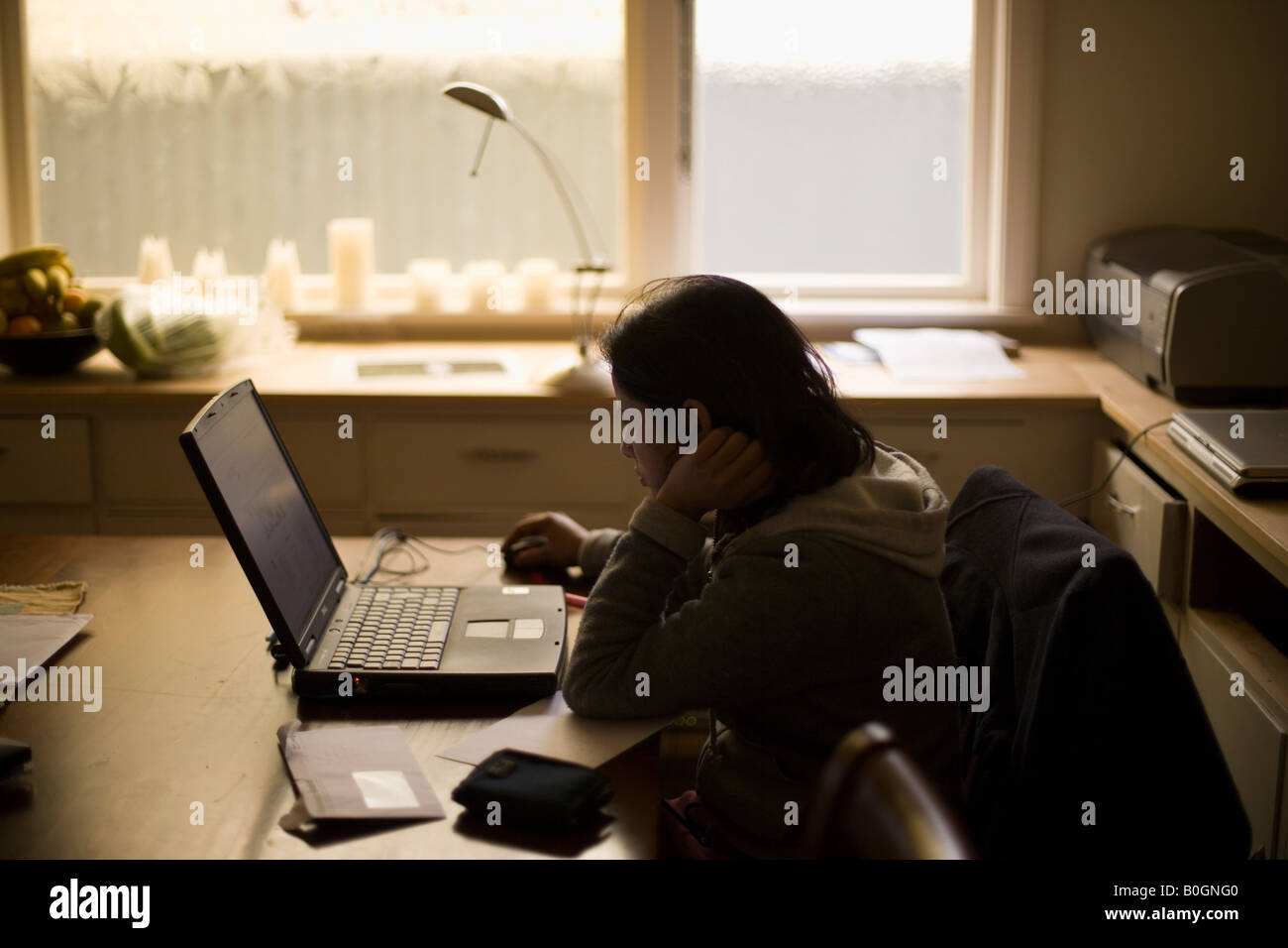 Asiatische Frau surft im Internet mit Laptop-Computer zu Hause am Esstisch aus Holz, die als ein Arbeitszimmer sich verdoppelt Stockfoto