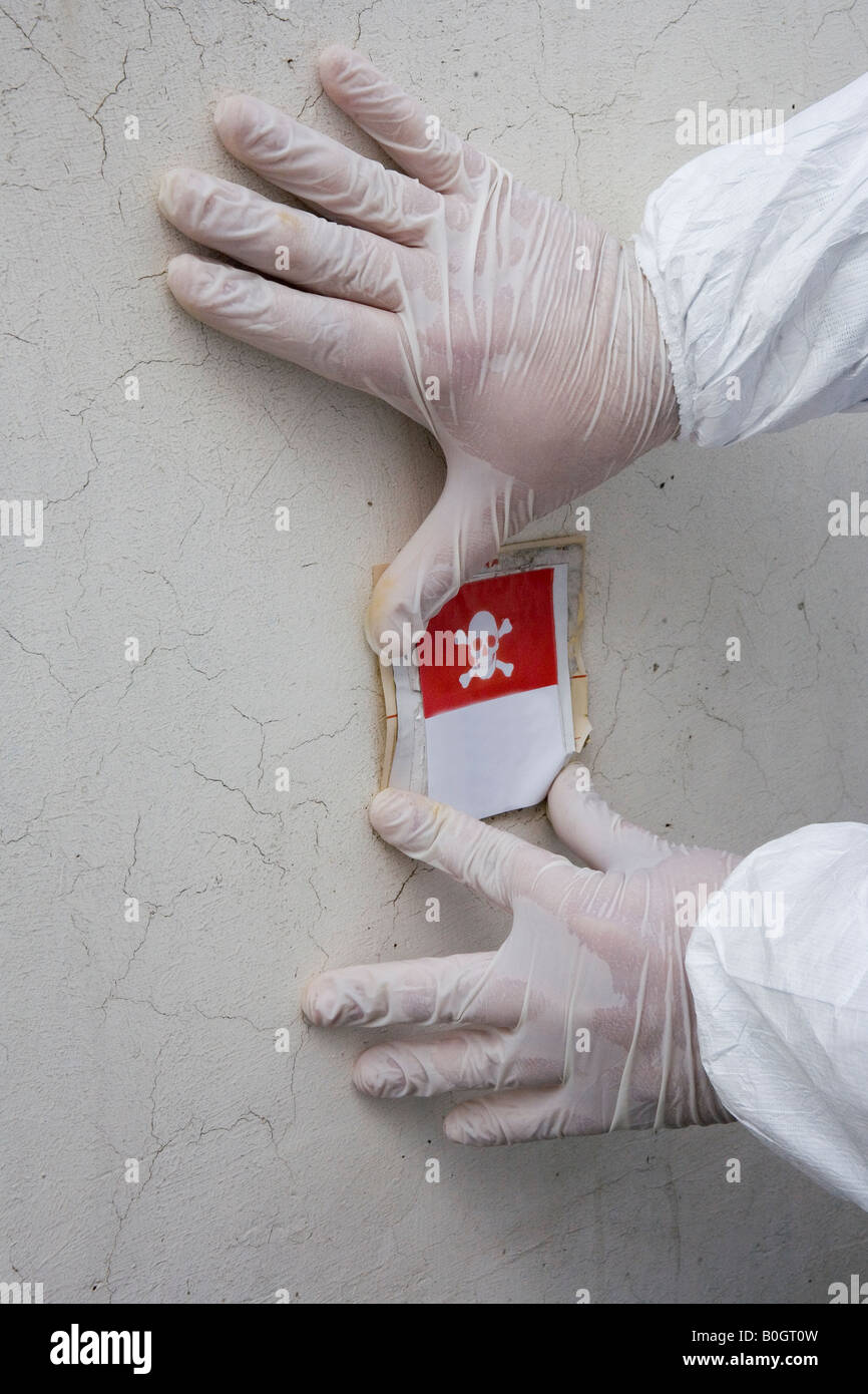 HÄNDE MIT HANDSCHUHEN SIND DAS SYMBOL DER SKULL AND BONES, DER ANGIBT, GEFAHR AN DER WAND PLATZIEREN Stockfoto