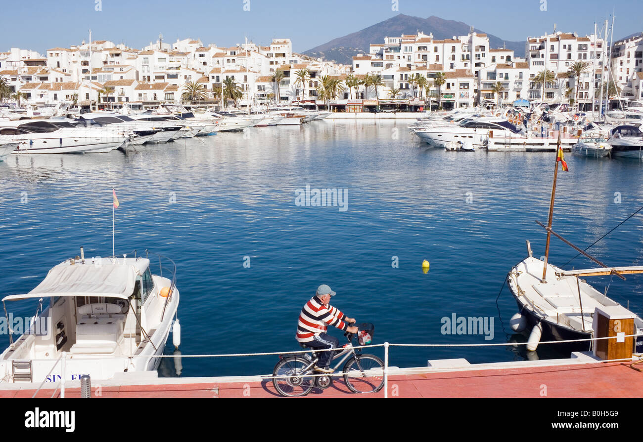 Marbella Costa del Sol Malaga Provinz Spanien Puerto Jose Banus Cyclist in gestreiften Pullover Reiten entlang des Hafens Stockfoto