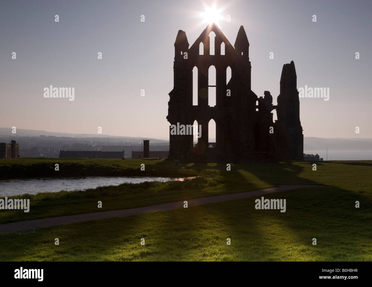 Whitby Abtei Yorkshire mit einer untergehenden Sonne über dem Giebel erfüllten die Ruine Stockfoto