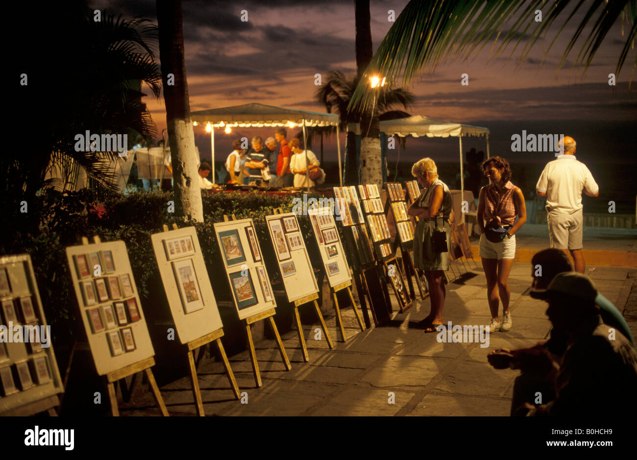 Kunstwerk zum Verkauf, bewundert von den Touristen an der Strandpromenade in der Abenddämmerung, Puerto Vallarta, Jalisco, Mexiko Stockfoto