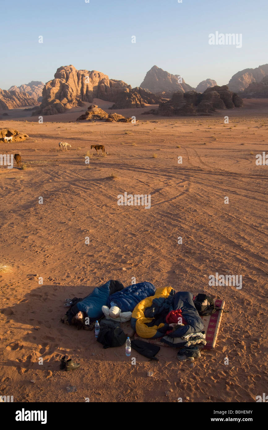 Touristen, die in einem Schlafsack unter freiem Himmel in der Wüste, Wadi Rum, Jordanien, Naher Osten Stockfoto