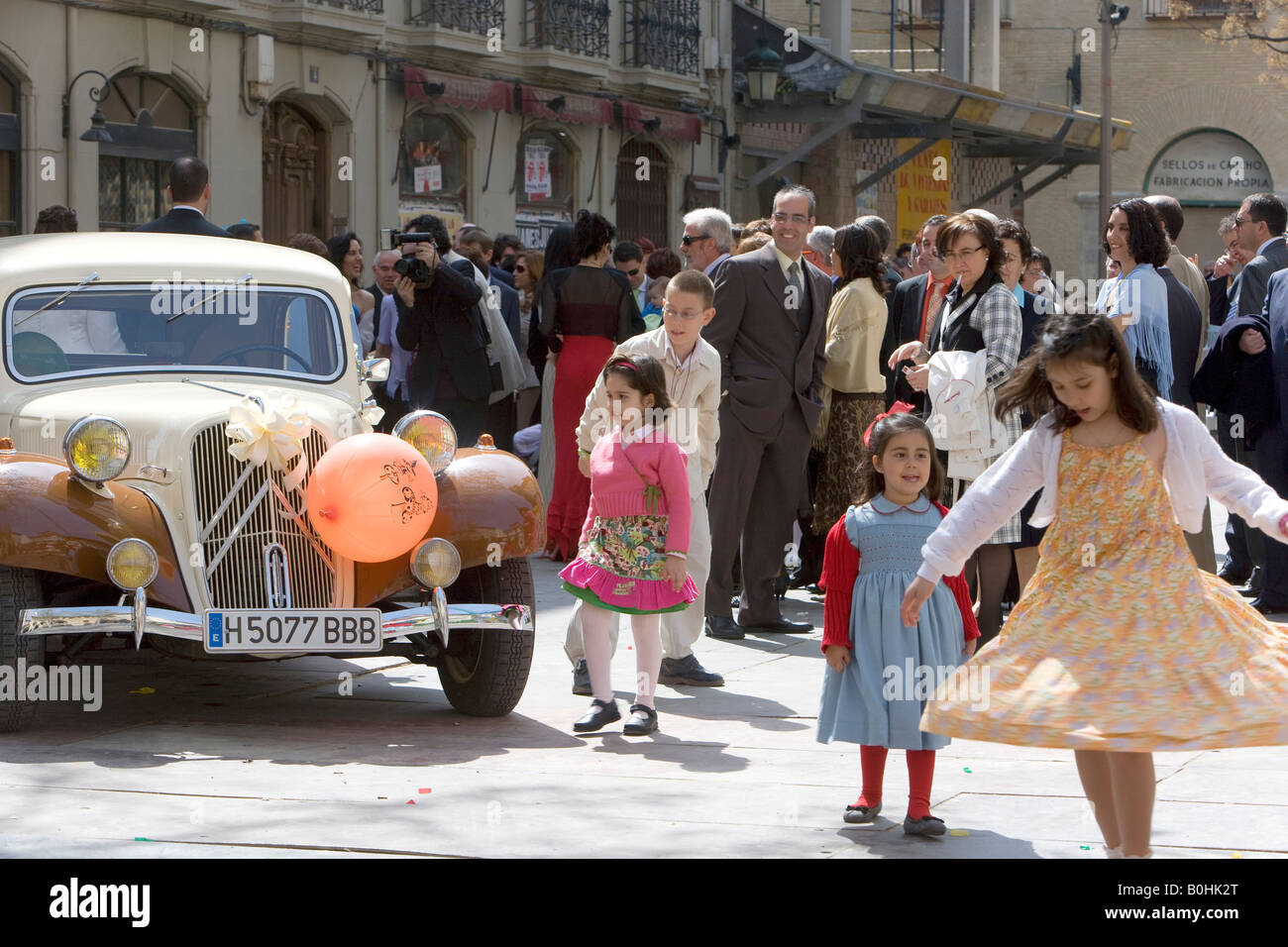 Mädchen auf einer Hochzeit tanzen vor einem Oldtimer dekoriert mit Luftballons und Blumen, Plaza San Felipe, Saragossa oder Stockfoto