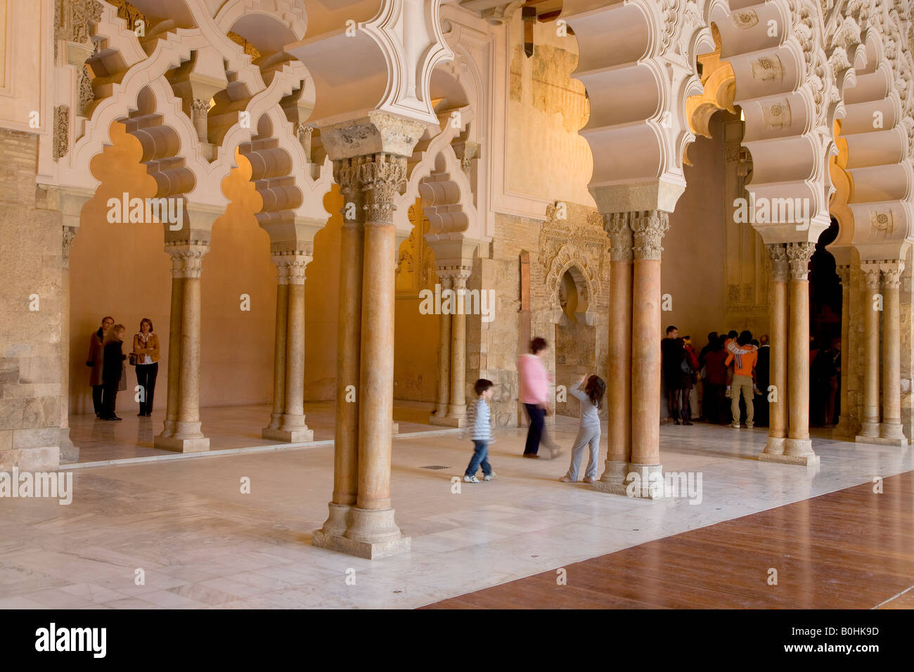 Touristen unter dem reich verzierten Stein geschnitzt gewölbten Durchgang des Santa Isabel Patios, Palacio de Aljaferia Palast, maurischer Bogen Stockfoto