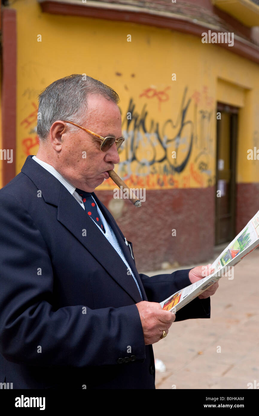 Lokalen spanischen Mann raucht eine Zigarre, während Lesen einer Zeitung vor einem Graffiti Wand in Zaragoza, Saragossa, Aragon gemalt, Stockfoto