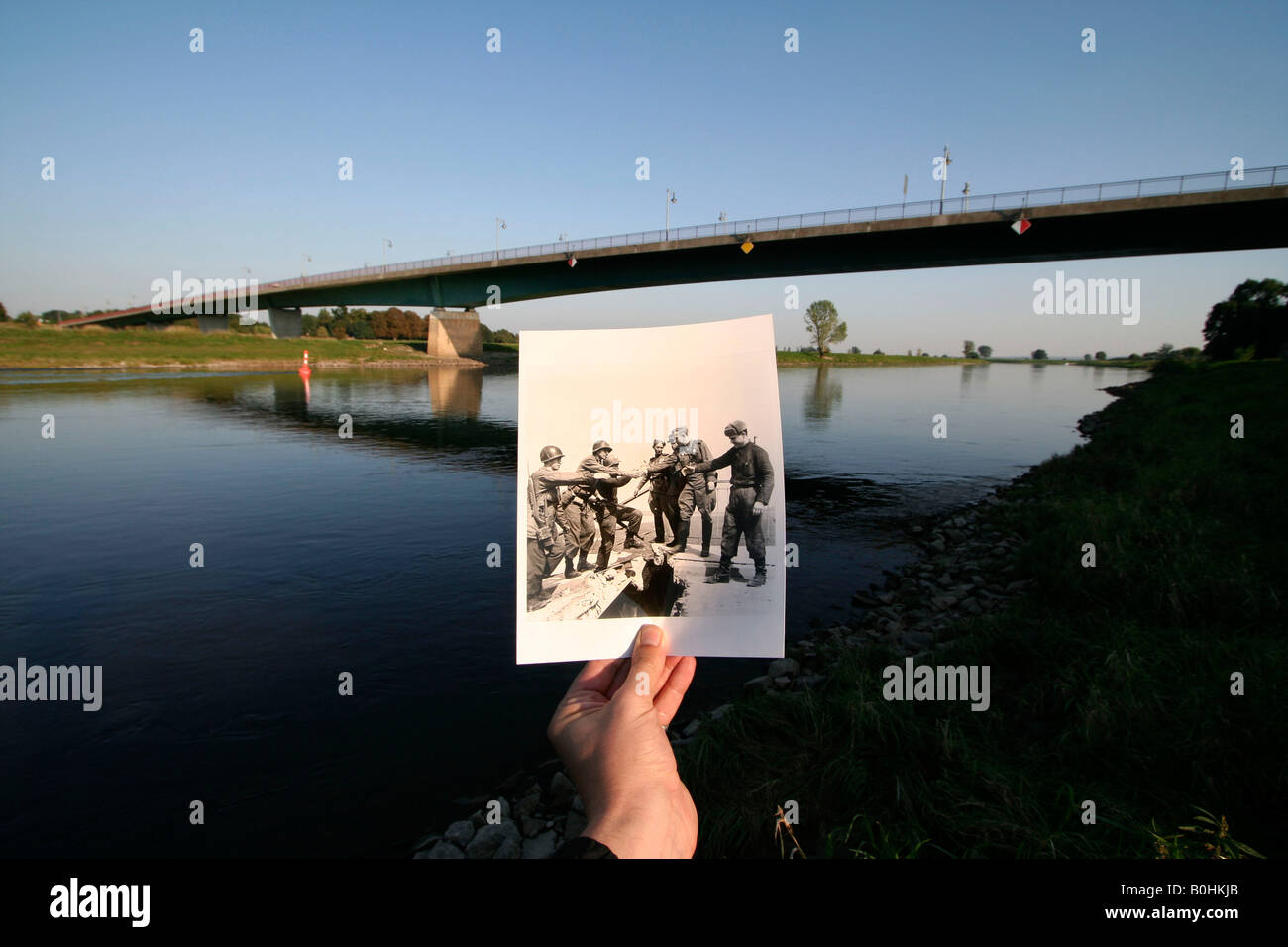 Damals und heute, Hand, die ein altes schwarz-weiß Foto von sowjetischen und amerikanischen Truppen am 25. April 1945 an der Elbbruec Stockfoto