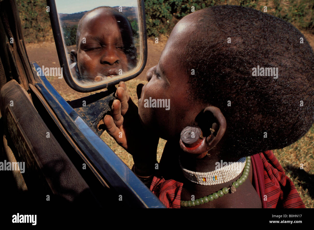 Ein Masai Kind betrachten sich selbst in einem Auto Seitenspiegel, Tansania. Stockfoto