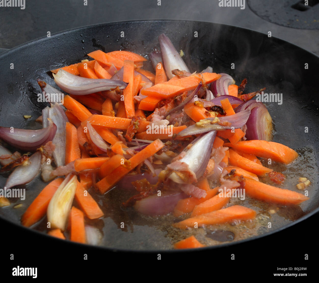 Braten, Karotten, Zwiebeln und getrockneten Tomaten mit einer sichtbaren Dampf Stockfoto