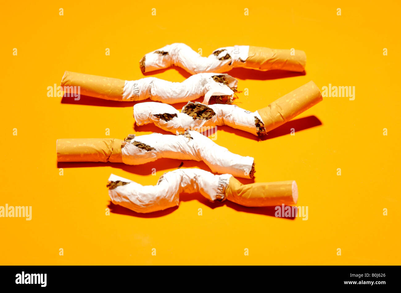 5 zerdrückte Zigaretten auf einem hellen orange Hintergrund Stockfoto
