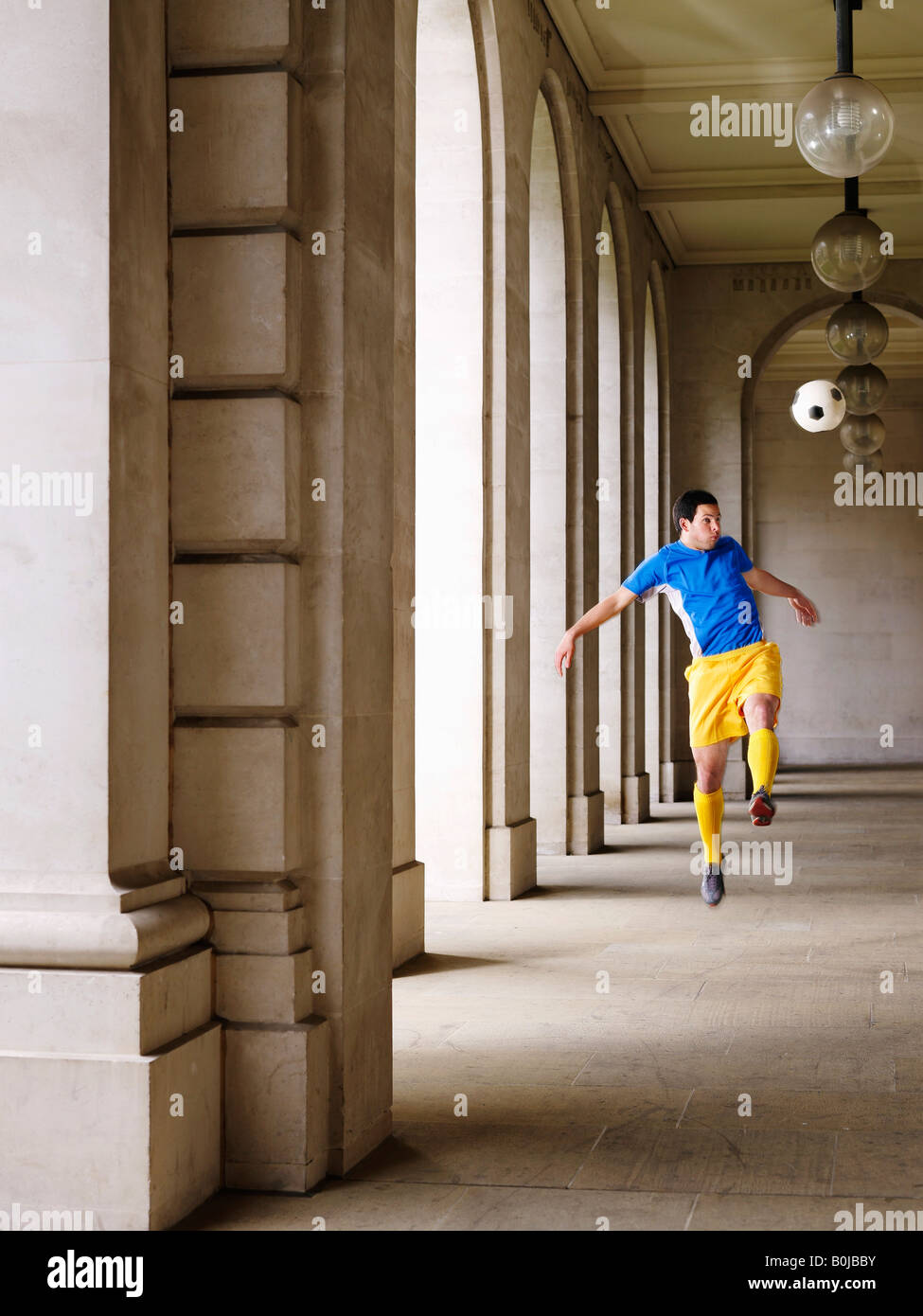 Fußball-Spieler treten Ball im Portikus Stockfoto
