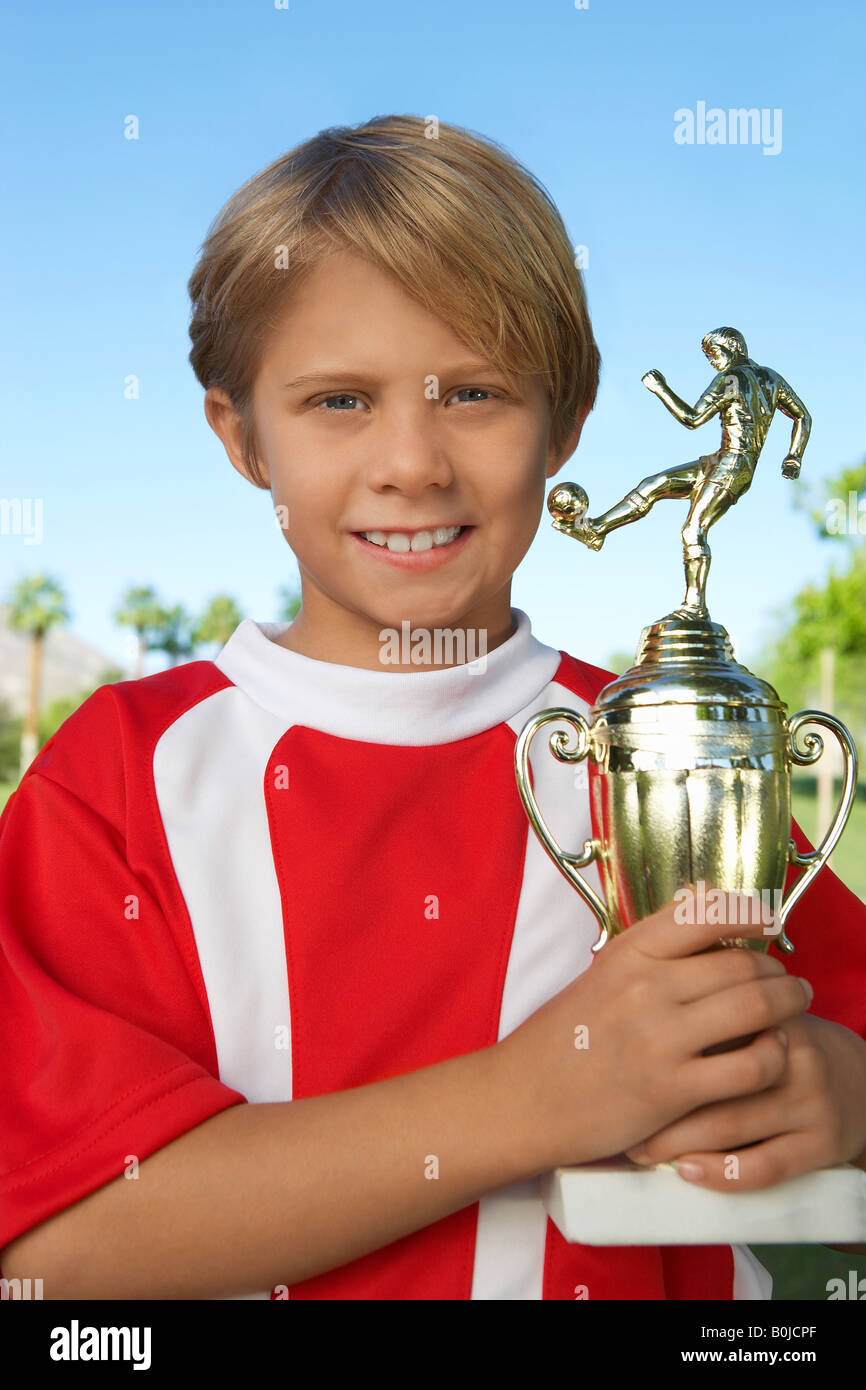 Boy (7-9 Jahre) Fußball Spieler Holding Trophy, Porträt Stockfoto
