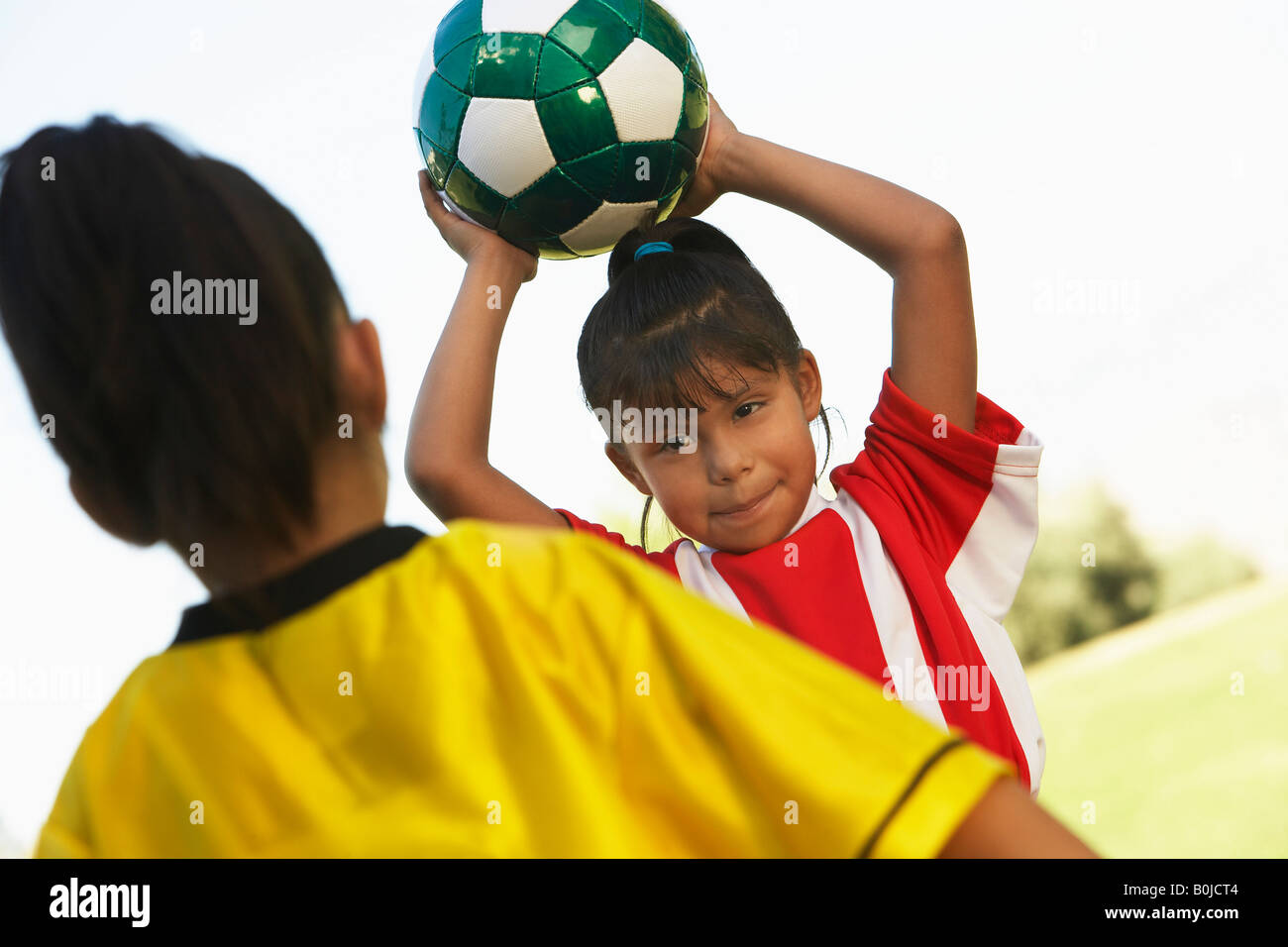 Mädchen-Fußball-Spieler (7-9 Jahre) vorbereiten, Ball werfen Stockfoto