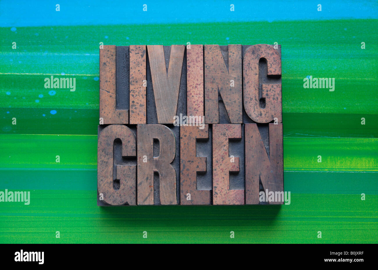 die Phrase "Living Green" im Buchdruck Holzart auf einem grünen und blauen Hintergrund Stockfoto