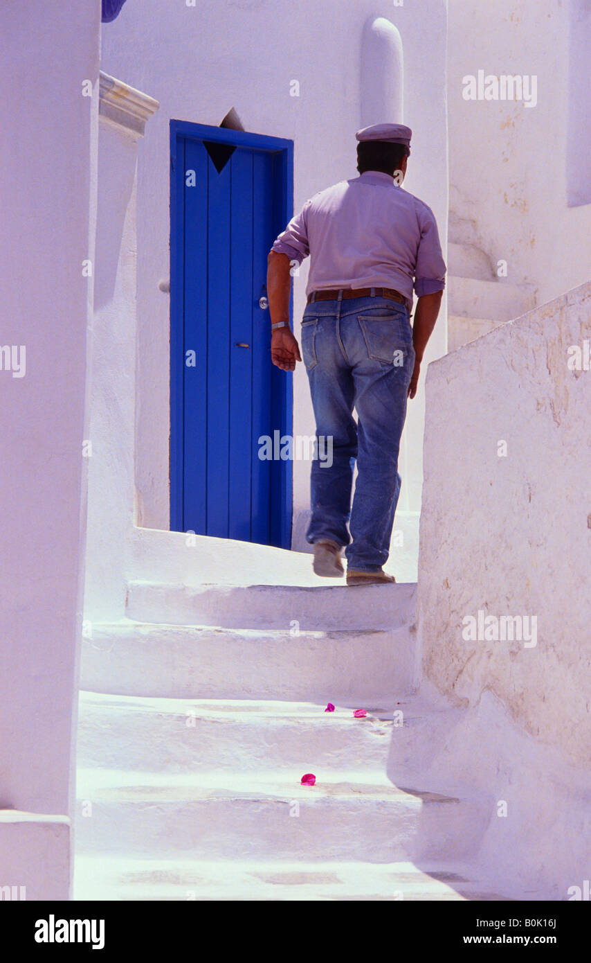 Mann zu Fuß passieren eine blaue Tür oben auf der Treppe in einer Gasse Mykonos Griechenland Stockfoto