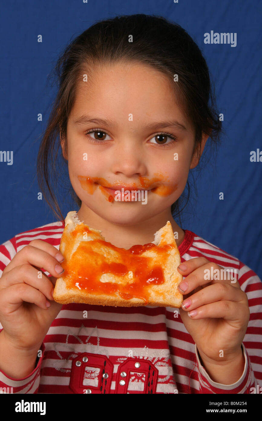 Junges Mädchen in einer chaotischen Weise ein Marmelade Sandwich zu essen. Stockfoto