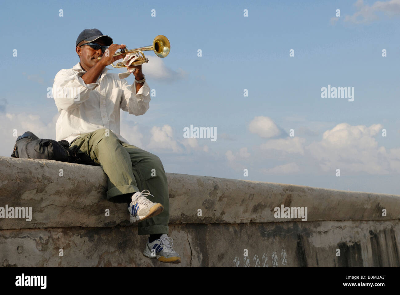 Ein Mann mittleren Alters auf einer Mauer sitzend und Trompete am Malecon Boulevard in Havanna Kuba-April 2007 Stockfoto