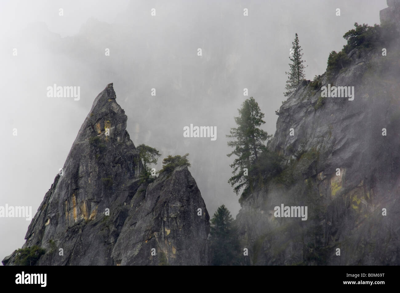 Scharfe gezackte spitzen Felsen Spire und Bäumen in Wolken Yosemite National Park in Kalifornien Stockfoto