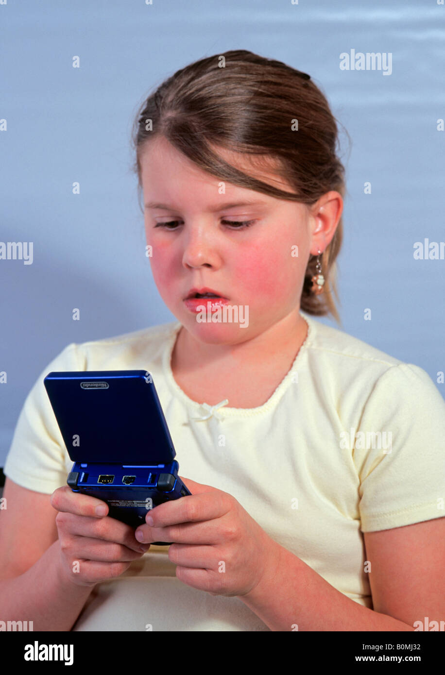 Ein 11 elfjährige Mittelschule Mädchen spielen auf ihrem gameboy Stockfoto