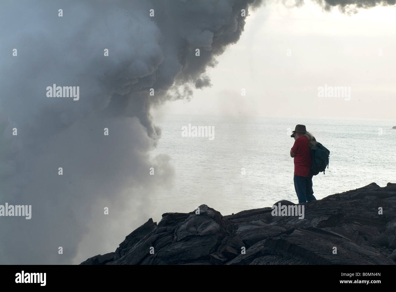 Mann fotografiert Dampf aus Lava fließt in das Meer, Hawaiʻi-Volcanoes-Nationalpark, Insel Hawaii (Big Island), Ha Stockfoto
