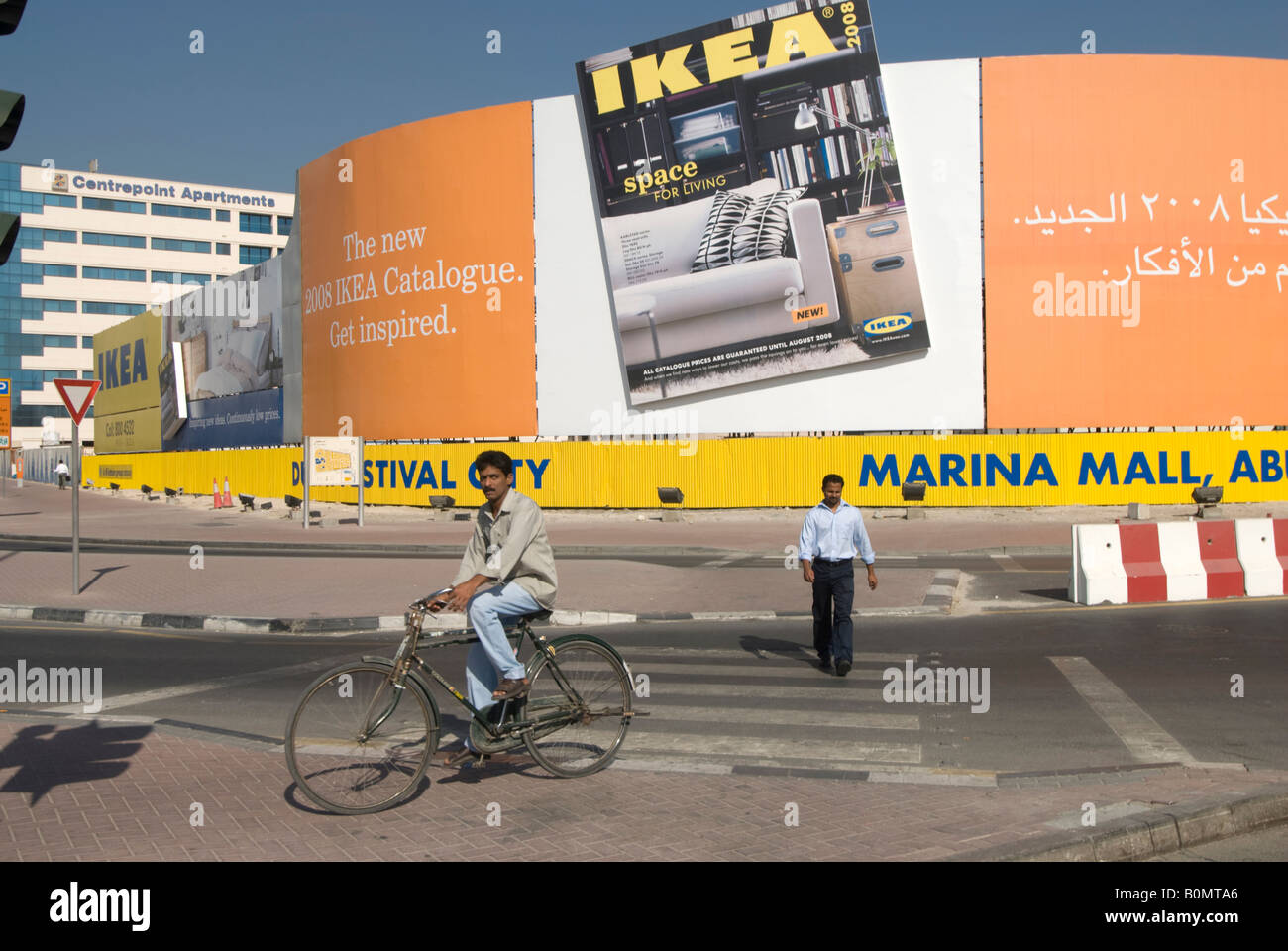 Ein ausländischer Arbeitnehmer verläuft vor einem IKEA Anzeige in einem Dubai Straße. /Travailleur migrant passe devant une Publicité pour IKEA/Werbung für Ikea. Stockfoto