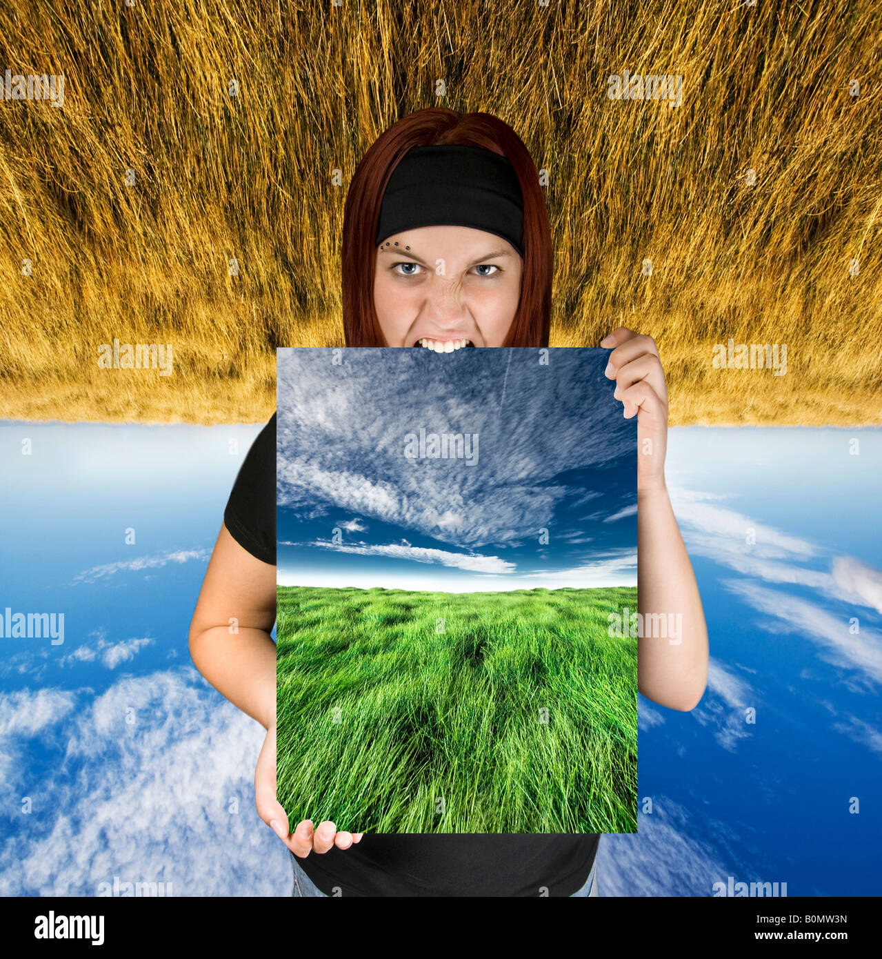 Rothaarige Mädchen hält eine blauer Himmel, grüne Feld Leinwand Hintergrund ist auf den Kopf nach unten mit dem Ausdruck ein Konzept von Reiseträume Stockfoto