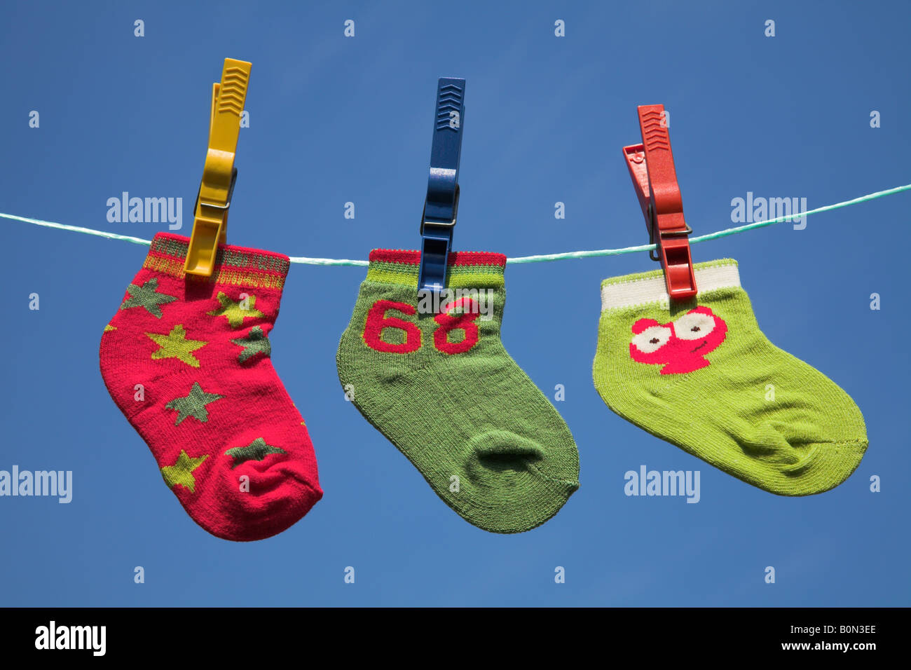 Drei verschiedene Baby-Socken auf einer Wäscheleine trocknen. Stockfoto