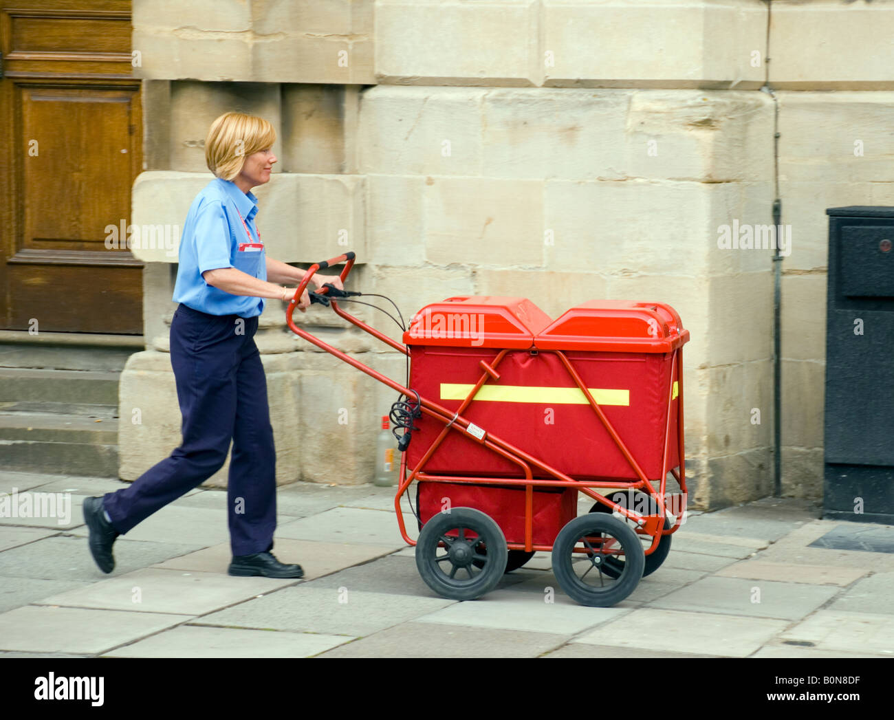 Bad BaNES England UK Frau Post Office Worker mit trolley Stockfoto