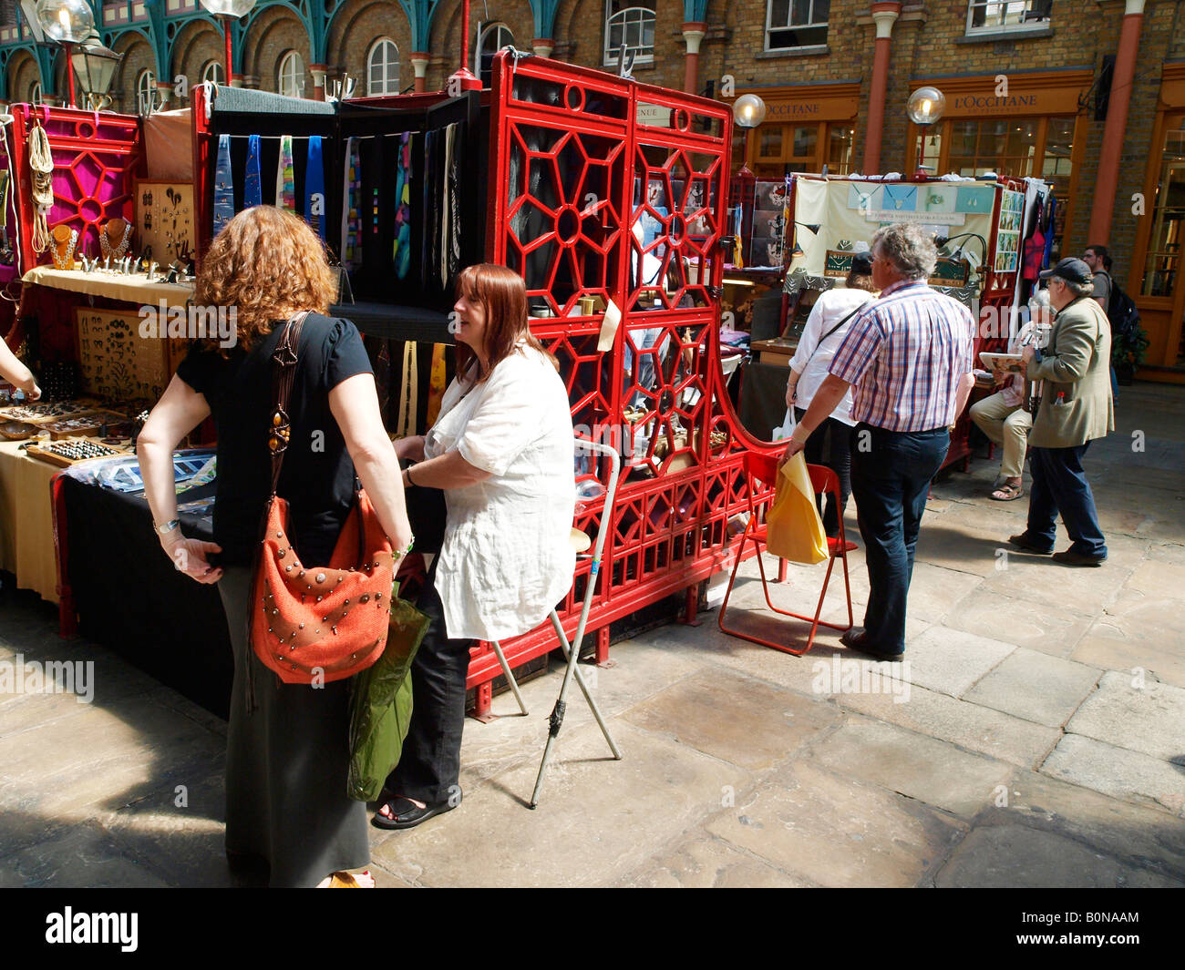 Touristen, die an den Ständen im Covent Garden Market London England einkaufen Stockfoto