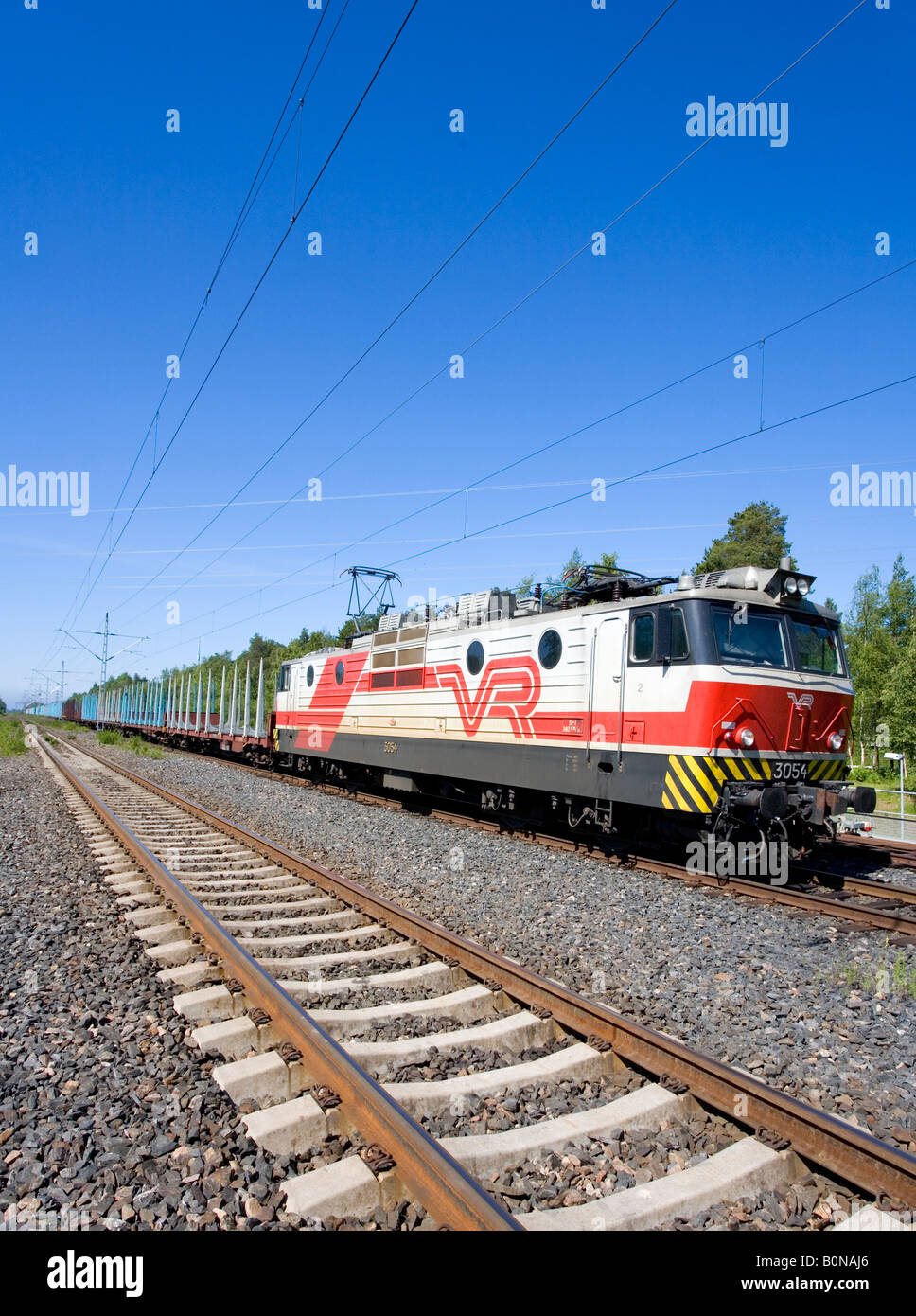 Langen Güterzug mit E-Lok und leeren flatcars für Verkehr anmelden. Moderne Betonschwellen (TIES) auf Schienen, Finnland Stockfoto