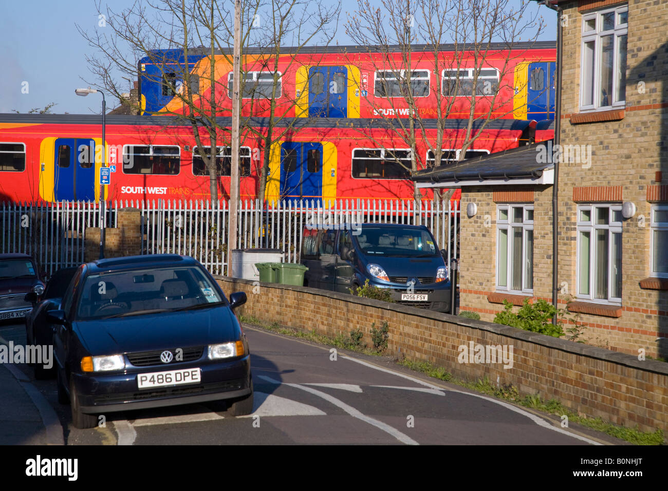 Zwei vorbeifahrenden Züge in einem Wohngebiet, auf verschiedenen Strecken und in der Nähe von parkenden Autos vorbei. Twickenham, Westlondon. VEREINIGTES KÖNIGREICH. Stockfoto