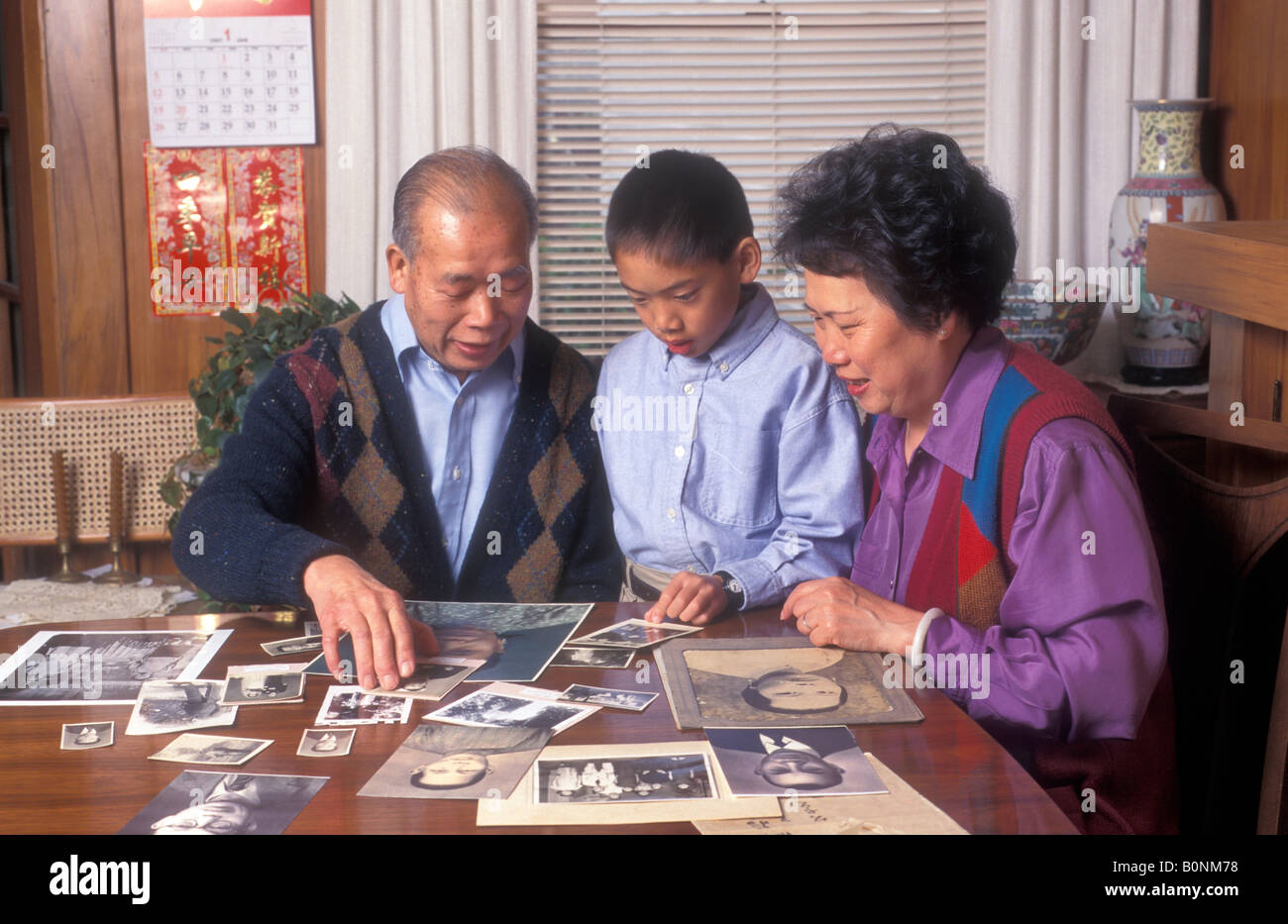 Chinesischen amerikanischen jungen Blick auf alte Familienfotos mit seinen Großeltern, San Francisco, Kalifornien, USA. Stockfoto