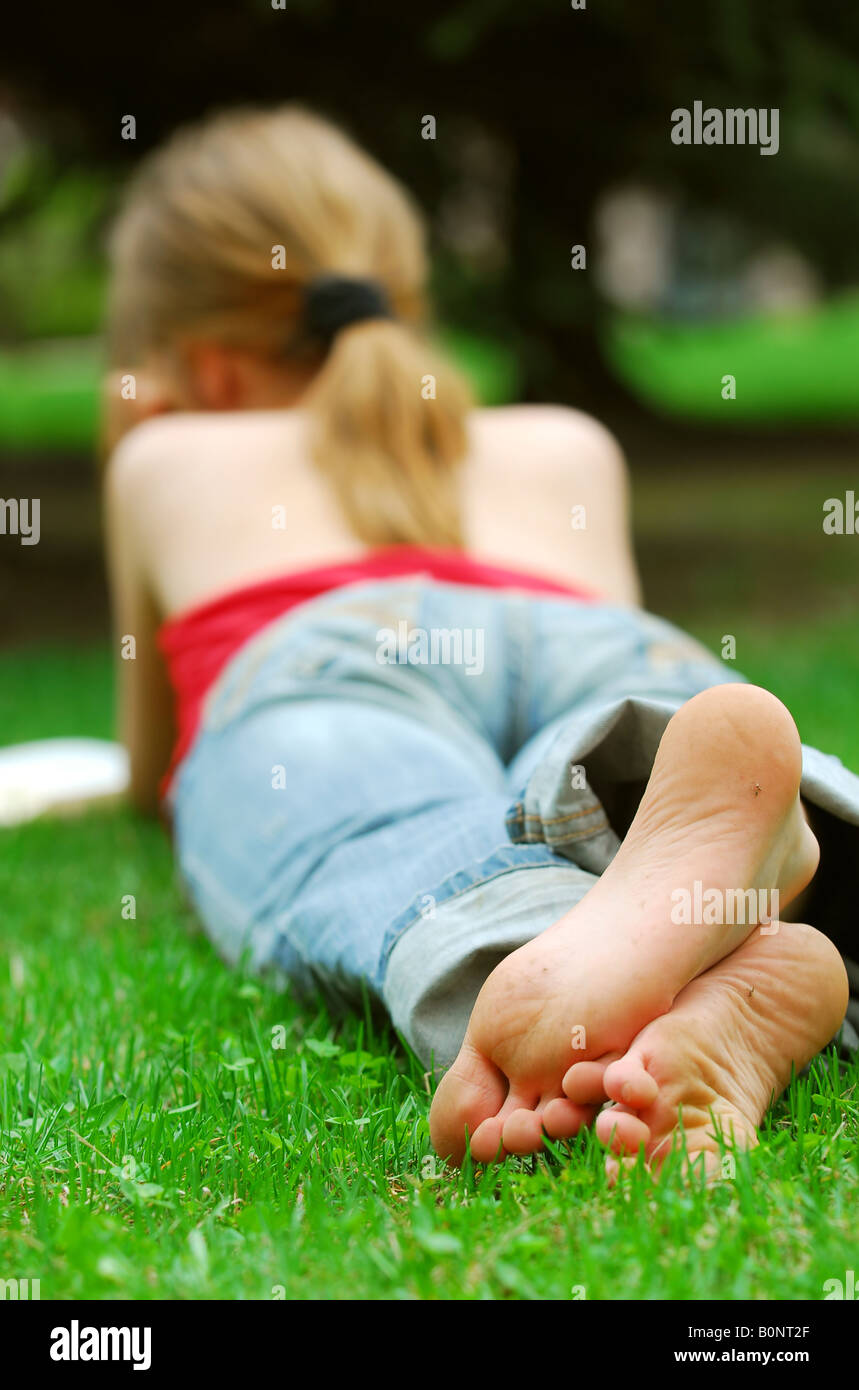 Junges Mädchen entspannen mit einem Buch auf dem grünen Rasen in einen Sommerpark Stockfoto