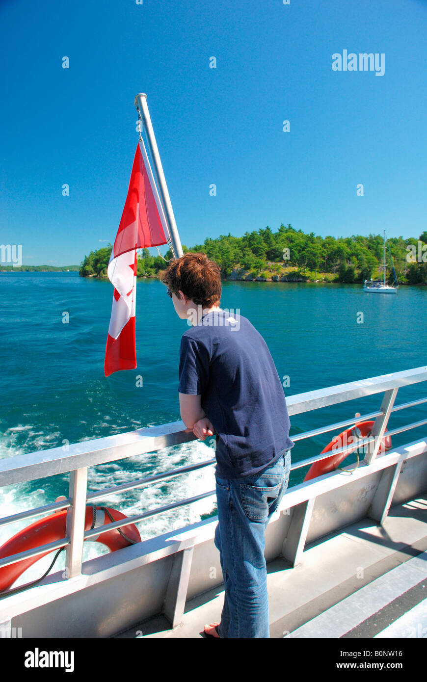 Kind auf der Suche über Heck von tausend Inseln Sportboot mit kanadischer Flagge Stockfoto