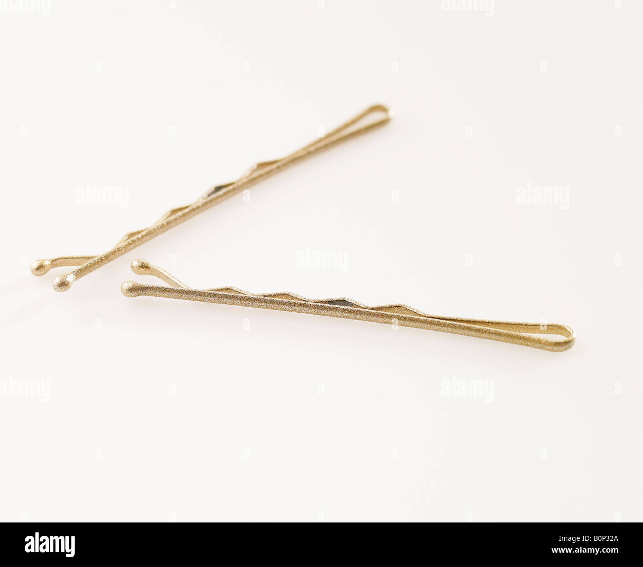 Zwei goldene Bobby Pins auf weißem Hintergrund Stockfoto