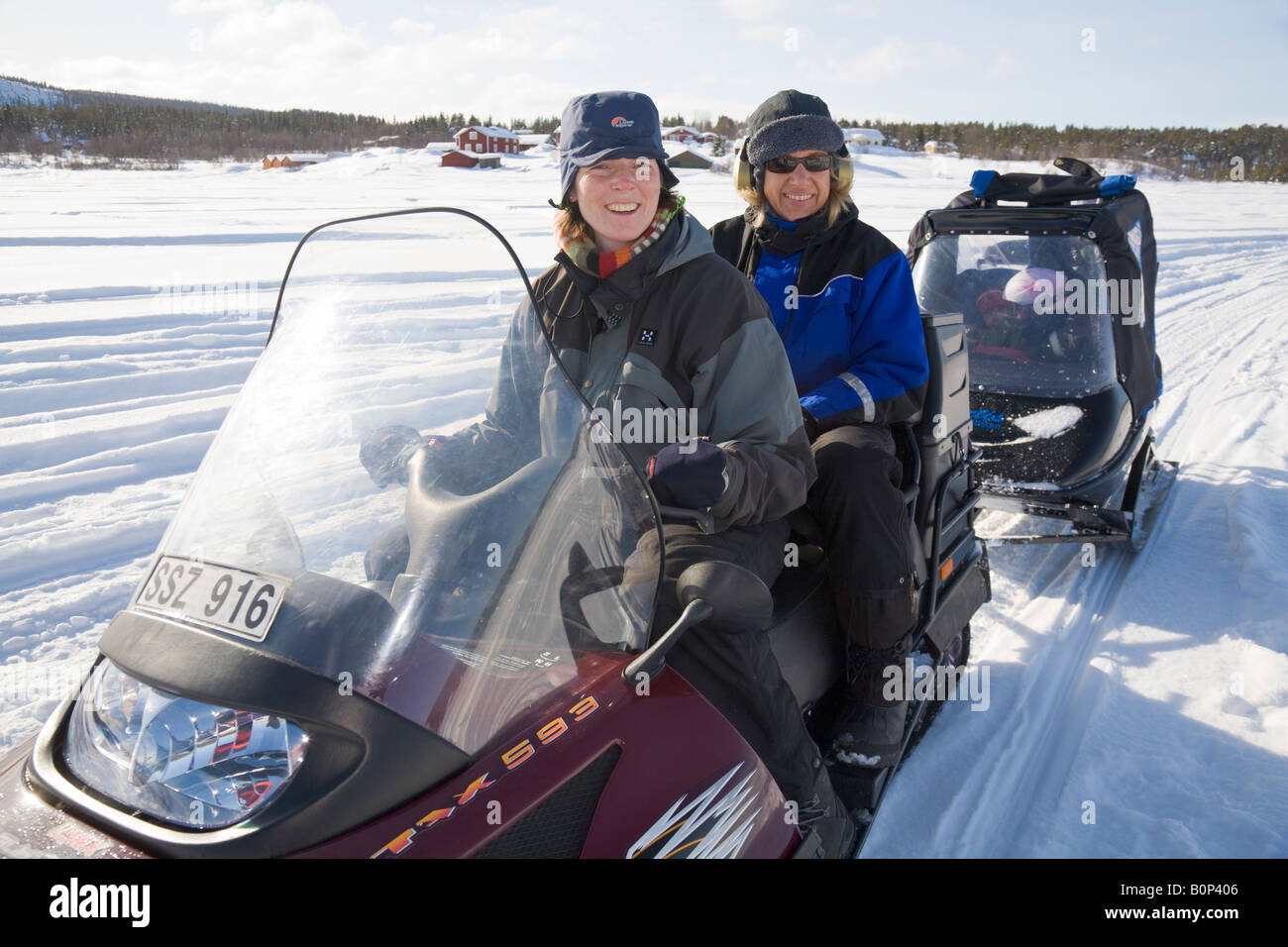Zwei Frauen in ihre vierziger fahren Lynx Motorschlitten mit einem Anhänger genannt Pulka im verschneiten Lappland / nördlichen Schweden Stockfoto