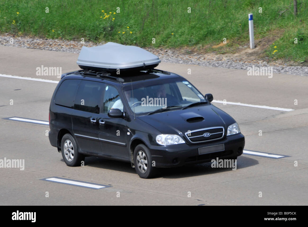 Kia Auto Dachbox auf Autobahn verdeckt Nummernschild und getönte Scheiben Stockfoto