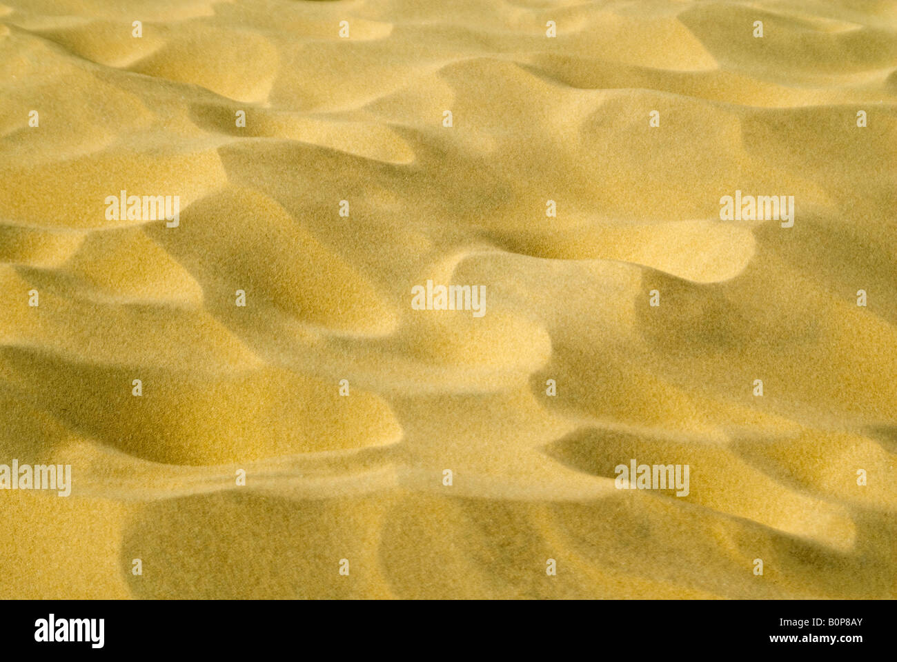 Horizontale Nahaufnahme der Muster in den Sand am Strand vom Wind an einem sonnigen Tag gemacht. Stockfoto