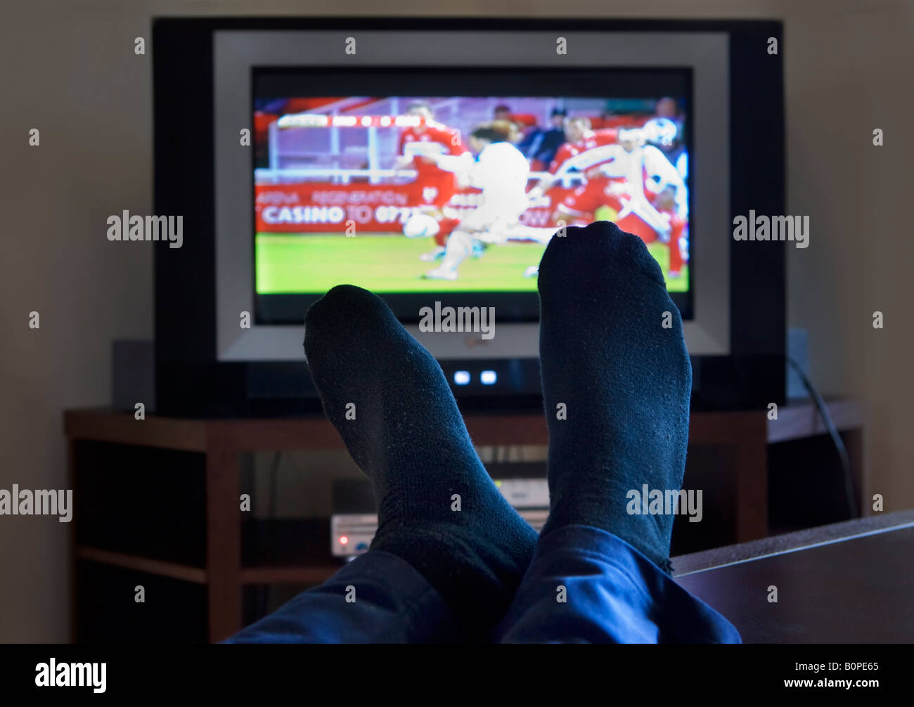 Ein Mann mit den Füßen auf die Fußball im Fernsehen gucken Stockfoto