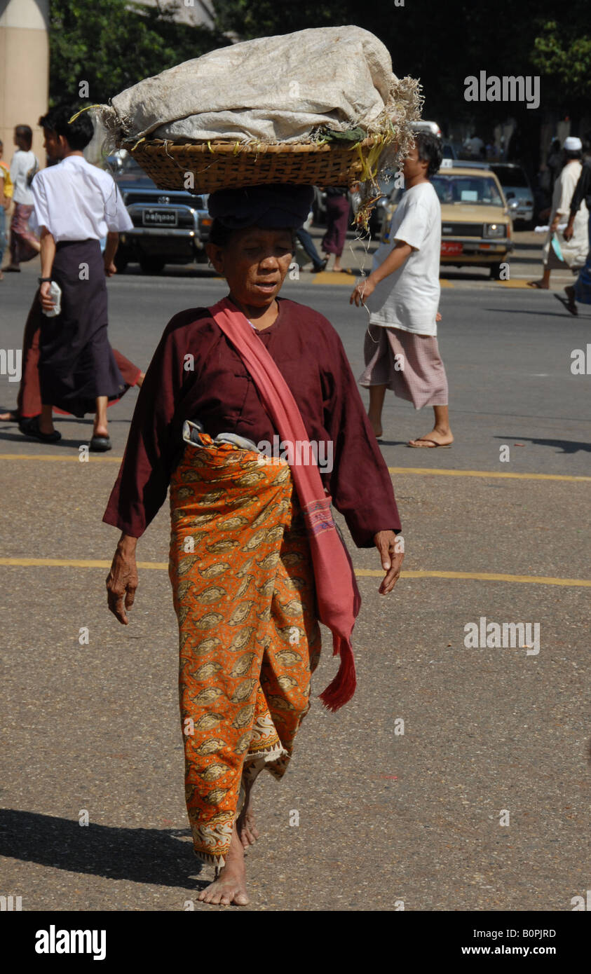 burmesische Dame tragen ihre Sachen auf ihren Kopf zu Fuß entlang der Straße, Rangun, burma Stockfoto