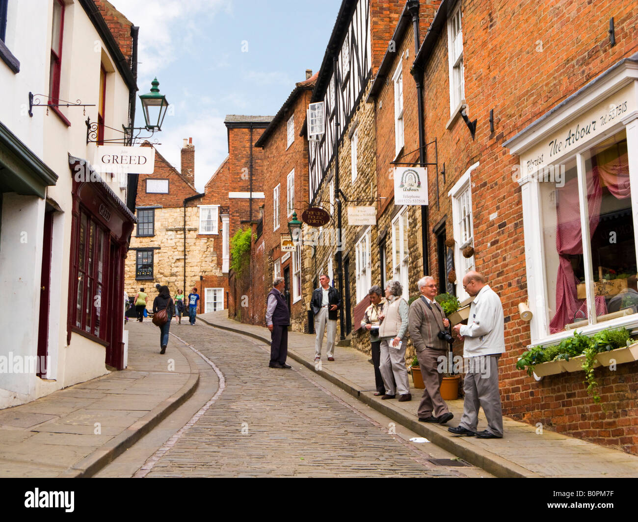 Touristen auf der historischen Kopfsteinpflasterstraße von Steilhang Hill in Lincoln, England, Großbritannien Stockfoto