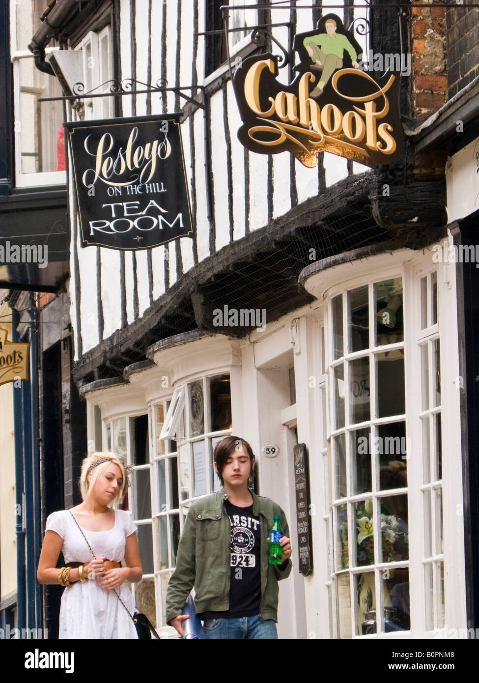 Touristen zu Fuß steil bergab in Lincoln, vorbei an einem traditionellen Teestube shop England UK Stockfoto